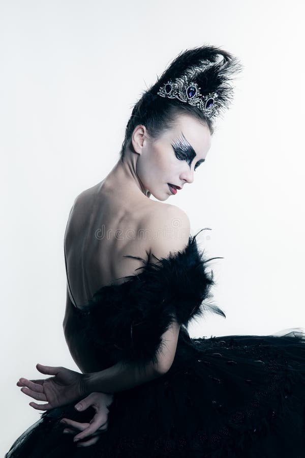 Studio shot of young ballerina wearing black tutu, stage dress and bright make-up posing isolated on white studio