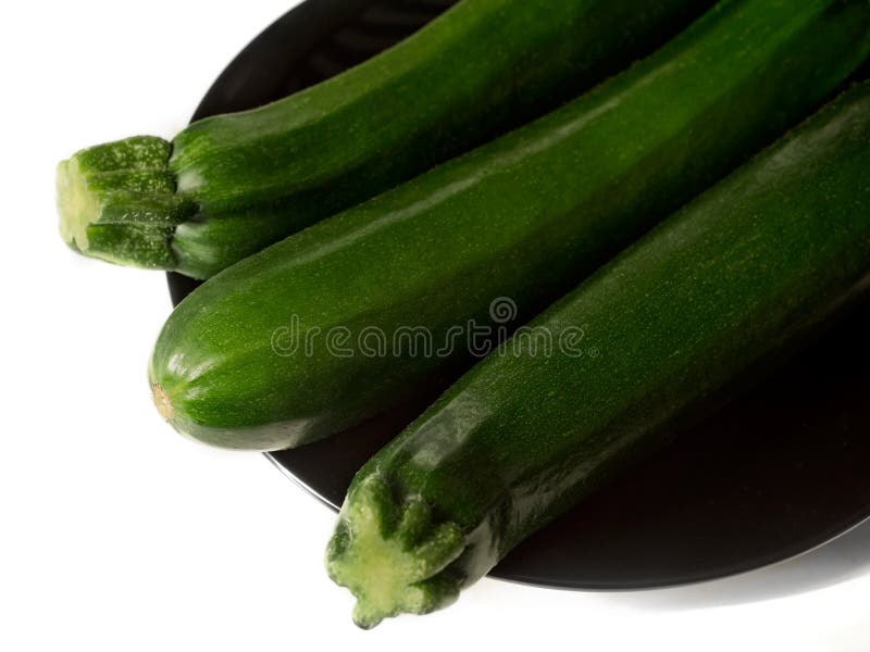 Studio strzelał trzy zucchinis na czarnym talerzu - odizolowywającym na bielu zdjęcia stock Studio strzelał trzy zucchinis na czarnym talerzu - odizolowywającym na bielu zdjęcia stock