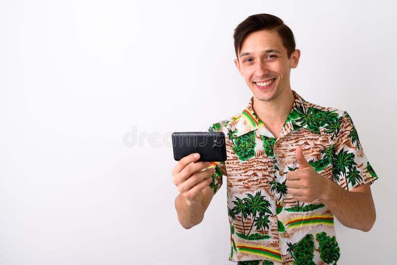 Studio tiré du jeune homme de touristes heureux souriant tout en donnant le thum photo stock Studio tiré du jeune homme de touristes heureux souriant tout en donnant le thum photo stock