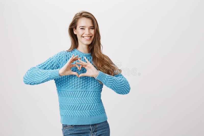 Studioportret van gevoels mooi meisje die hartgebaar tonen en ruim terwijl het uitdrukken van haar houding tegenover glimlachen royalty-vrije stock foto's Studioportret van gevoels mooi meisje die hartgebaar tonen en ruim terwijl het uitdrukken van haar houding tegenover glimlachen royalty-vrije stock foto's