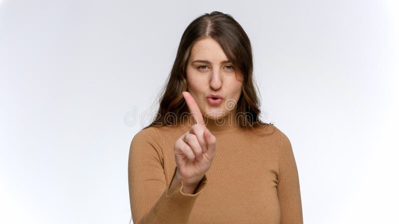 Studioporträt einer jungen Frau, die den Finger schüttelt und nein sagt. Verbotskonzept und Tabu