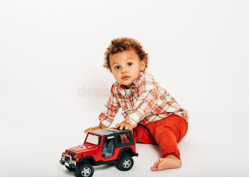 Studio shot of adorable african 1 year old baby boy playing with red car. Studio shot of adorable african 1 year old baby boy playing with red car