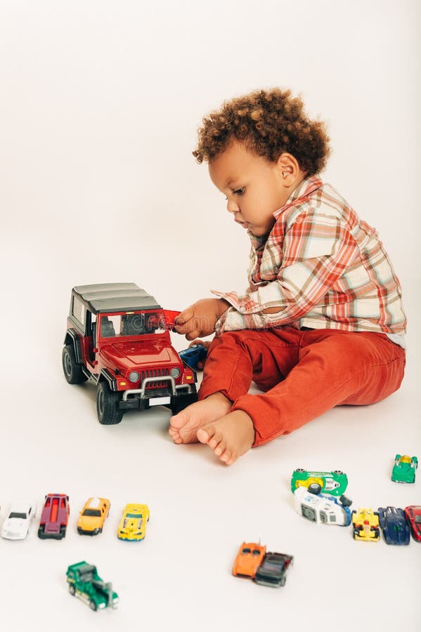 Studio shot of adorable african 1 year old baby boy playing with colorful mini cars. Studio shot of adorable african 1 year old baby boy playing with colorful mini cars