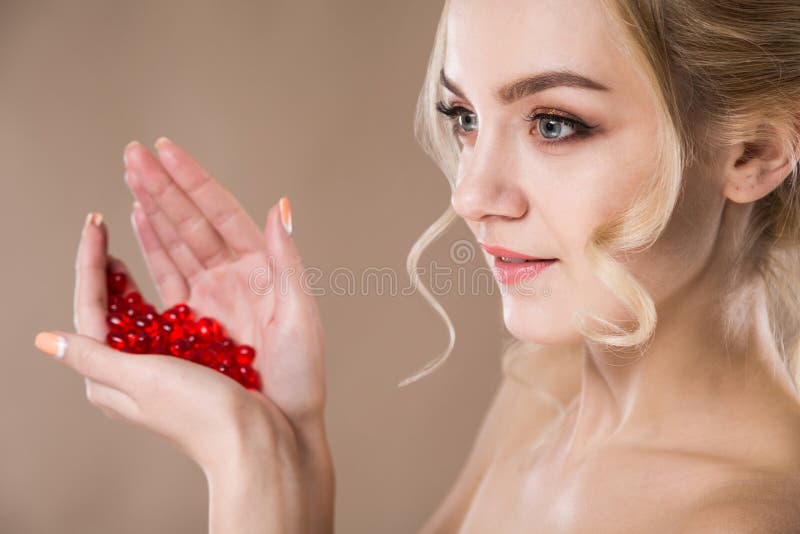 Studiostående av en blondin i henne röda kapslar för händer av vitaminet fotografering för bildbyråer Studiostående av en blondin i henne röda kapslar för händer av vitaminet fotografering för bildbyråer