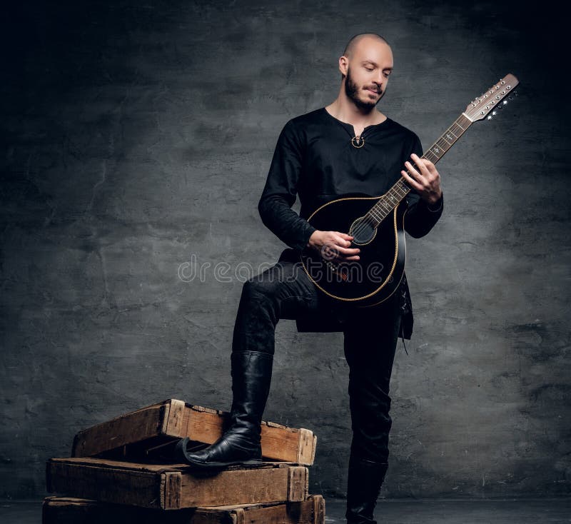 Studiostående av en man i traditionell keltisk kläder som spelar på mandolinen royaltyfri fotografi Studiostående av en man i traditionell keltisk kläder som spelar på mandolinen royaltyfri fotografi