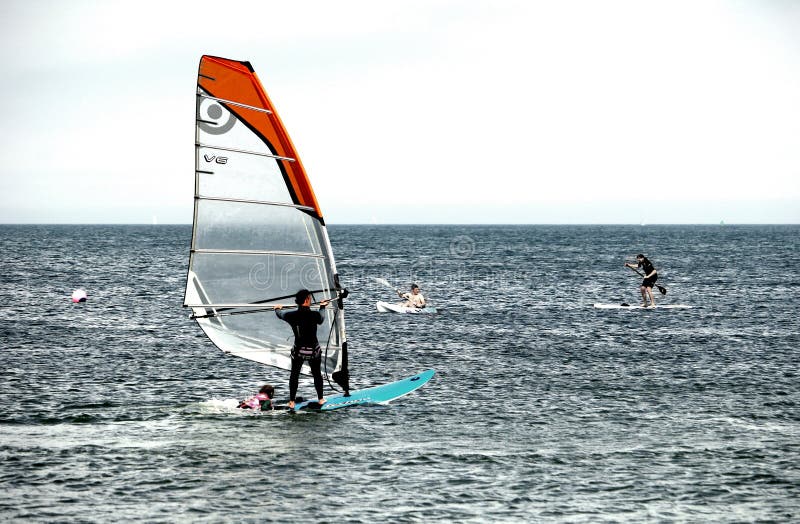 Studland, Dorset, England - June 01 2018: Holidaymakers swimming, windsurfing, kayaking and paddle boarding in the sea on the Sout royalty free stock photo Studland, Dorset, England - June 01 2018: Holidaymakers swimming, windsurfing, kayaking and paddle boarding in the sea on the Sout royalty free stock photo
