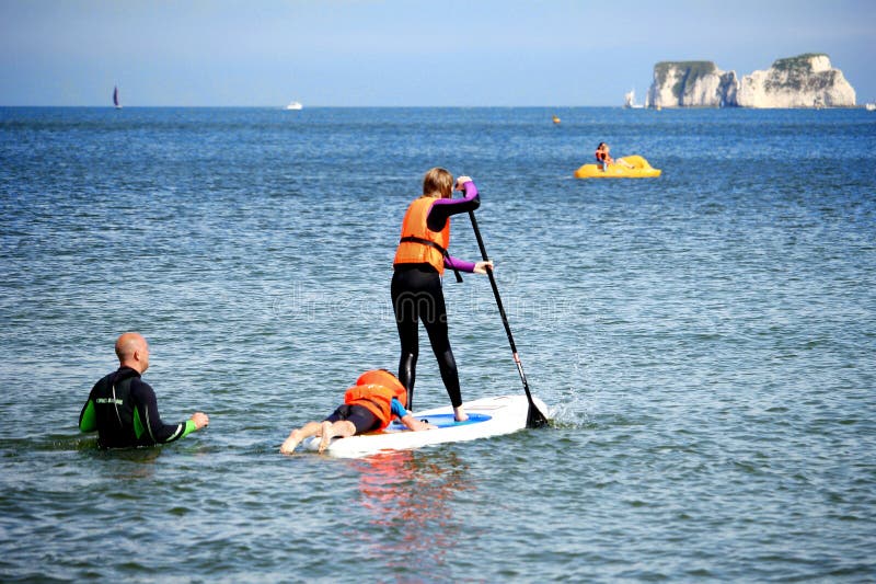 Studland, Dorset, England - June 01 2018: Holidaymakers swimming and paddle boarding in the sea near Old Harry rocks on the South Coast of England. Studland, Dorset, England - June 01 2018: Holidaymakers swimming and paddle boarding in the sea near Old Harry rocks on the South Coast of England