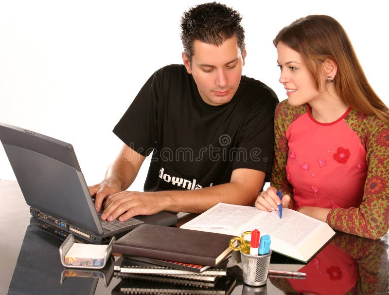 Giovani studenti che studiano insieme al tavolo con libri e computer portatile.