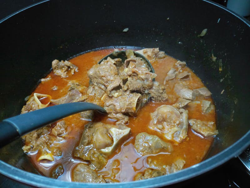 Juicy lamb stew cooking in a large pot With plastic serving ladle. Juicy lamb stew cooking in a large pot With plastic serving ladle