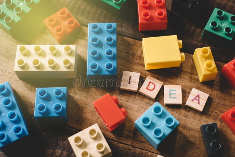 Stuk speelgoed plastic bakstenen op houten lijst met het woordidee van alfabettegels stock afbeeldingen Stuk speelgoed plastic bakstenen op houten lijst met het woordidee van alfabettegels stock afbeeldingen