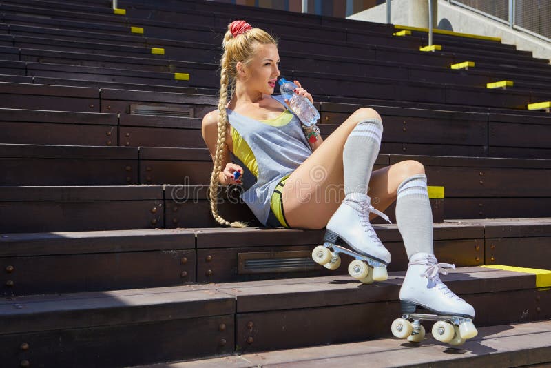 Happy woman posing in a vintage roller skates, T-shirt, shorts posing on a road in city  hot summer day. Holidays and vacations