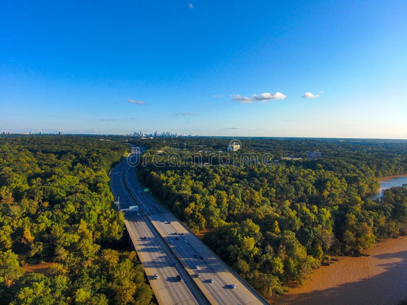 A stunning aerial shot of vast miles of lush green trees, the freeway, the Chattahoochee river and blue sky at sunset