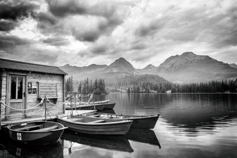 Ohromující černobílá krajina se zataženou oblohou, hory a jezero s výletními loděmi, štrbské pleso, vysoké tatry, slovensko