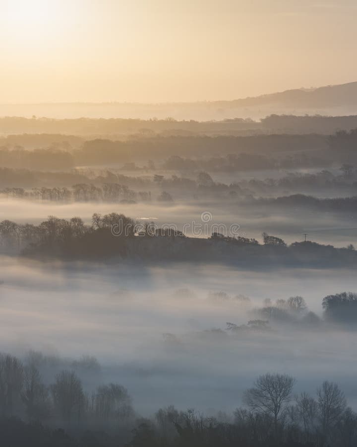 Stunning foggy English rural landscape at sunrise in Winter with
