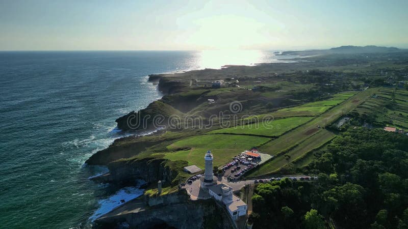 An aerial view showcases a stunning lighthouse by the coast, surrounded by lush greenery and calming ocean waves. Lighthouse viewpoint stock images, royalty-free photos and pictures