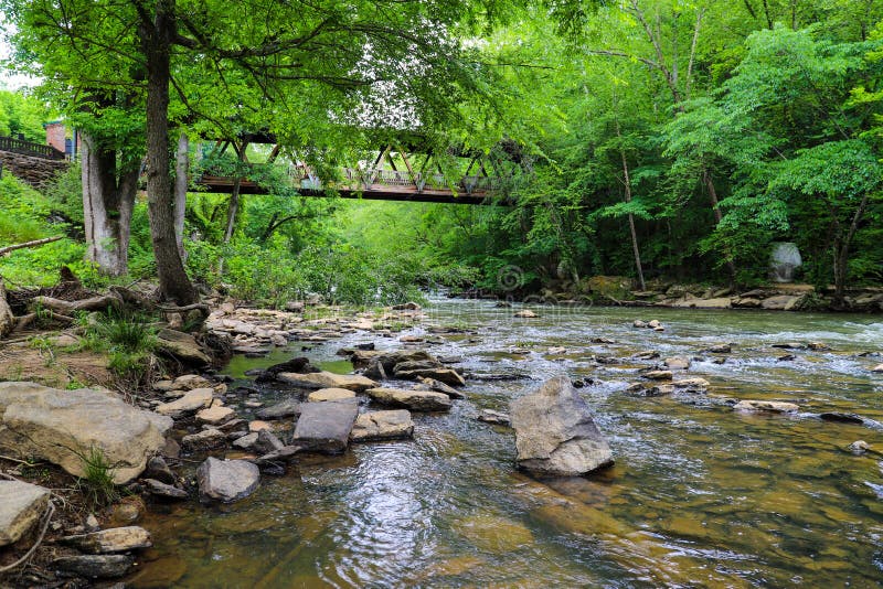 A stunning shot of the rushing river water of Big Creek river with lush green trees and large rocks on the banks