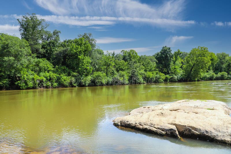 Ohromující z hedvábný hnědý vody z řeka rozsáhlý km z bujný zelený stromy podél řeka velký skály přes voda modrá obloha silný mraky na rezerva v gruzínsko spojené státy americké.