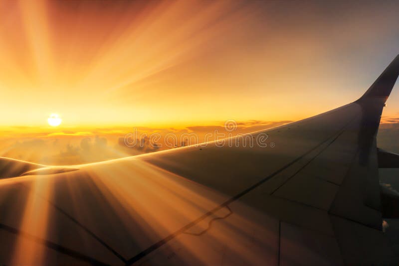 Stunning Sunrise Traveling Over Clouds On Plane With Sunbeams Over Wings Through Window