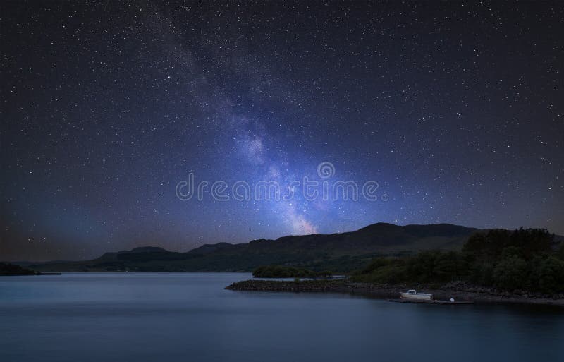 Stunning vibrant Milky Way composite image over landscape of calm lake with boat on shore royalty free stock photography Stunning vibrant Milky Way composite image over landscape of calm lake with boat on shore royalty free stock photography