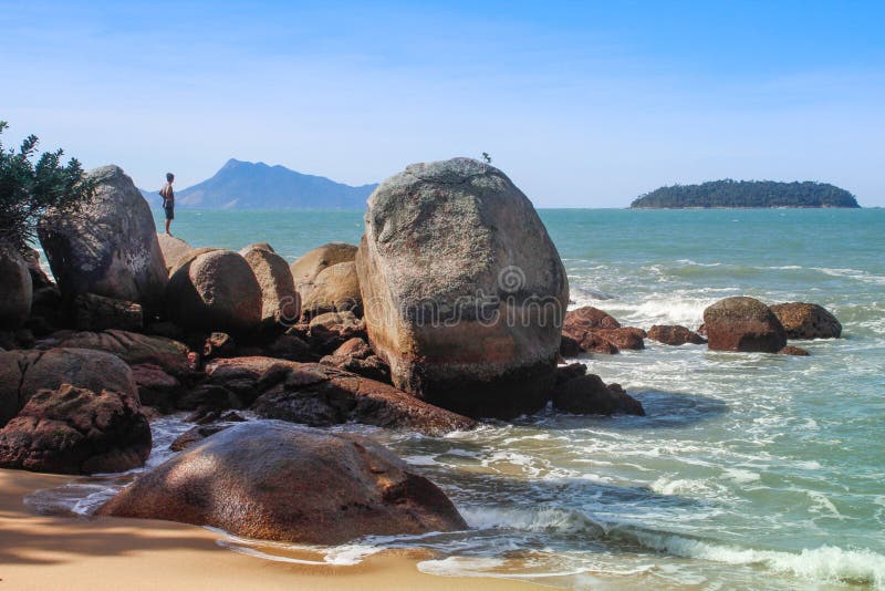 Stunningly beautiful beach with turquoise water, stones and rocks. A man stands on a stone. Landscape with the beach of Brazil on stock photo Stunningly beautiful beach with turquoise water, stones and rocks. A man stands on a stone. Landscape with the beach of Brazil on stock photo