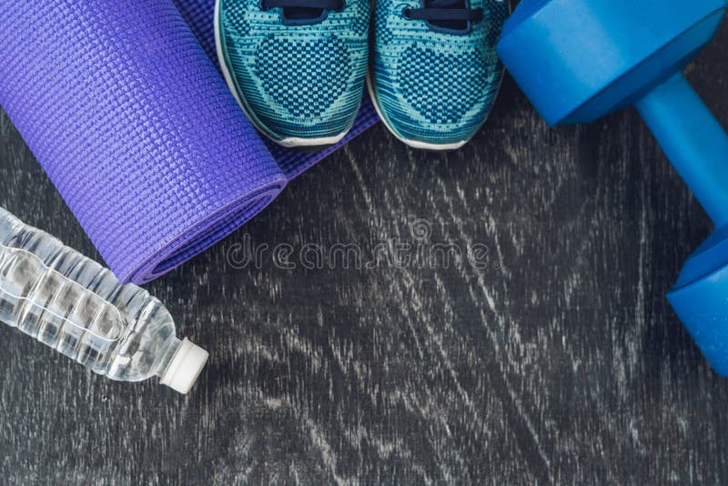 Yoga mat, sport shoes, dumbbells and bottle of water on blue background. Concept healthy lifestyle, sport and diet. Sport equipment. Copy space. Yoga mat, sport shoes, dumbbells and bottle of water on blue background. Concept healthy lifestyle, sport and diet. Sport equipment. Copy space.