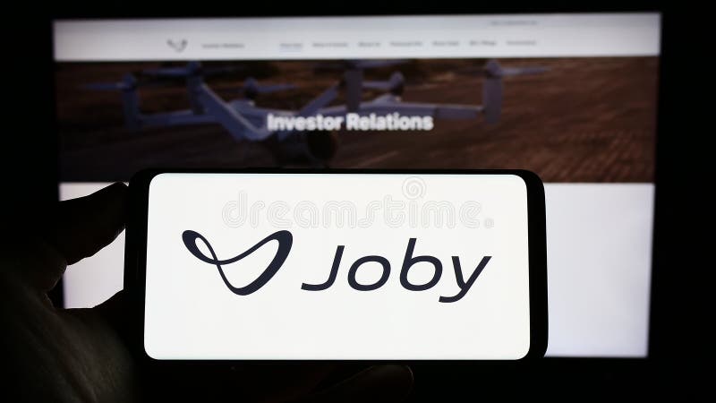 Stuttgart, Germany - 03-31-2023: Person holding cellphone with logo of US eVTOL company Joby Aviation on screen in front of business webpage. Focus on phone display.