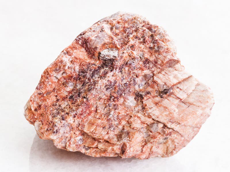 Stycke av den rosa granitstenen på vit marmor royaltyfria bilder