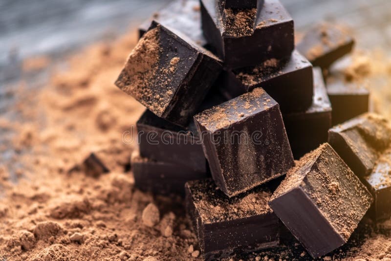 Stycken av mörk bitter choklad med kakaopulver på mörk träbakgrund Begrepp av konfektingredienser royaltyfria foton Stycken av mörk bitter choklad med kakaopulver på mörk träbakgrund Begrepp av konfektingredienser royaltyfria foton