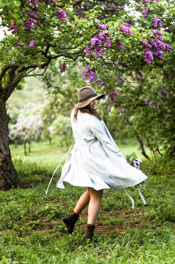 Stylis happy girl dancing in the  lilac garden