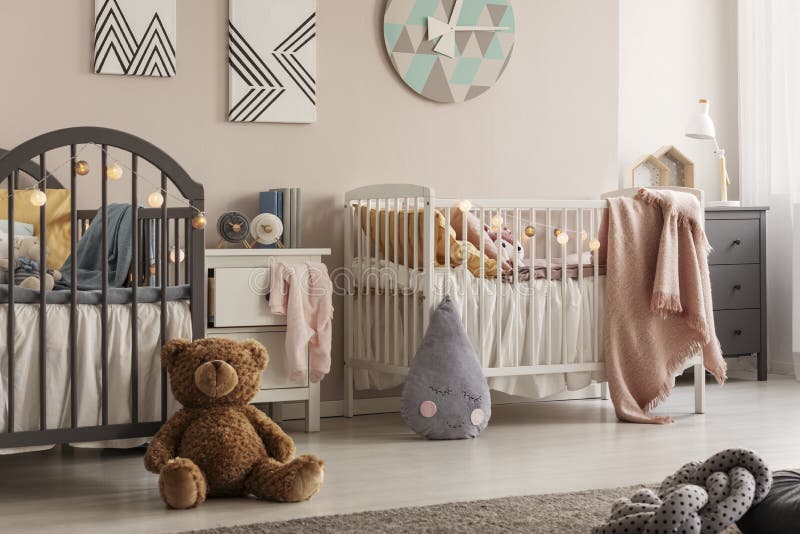 Stylish Baby Bedroom For Twins With Two Cribs And Teddy Bear On