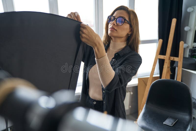 Serious young woman preparing studio for shooting