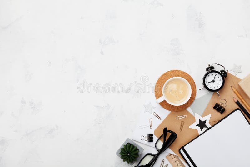 Stylish blogger working desk with coffee, office supply, alarm clock and clean notebook on white table top view. Flat lay. stock image