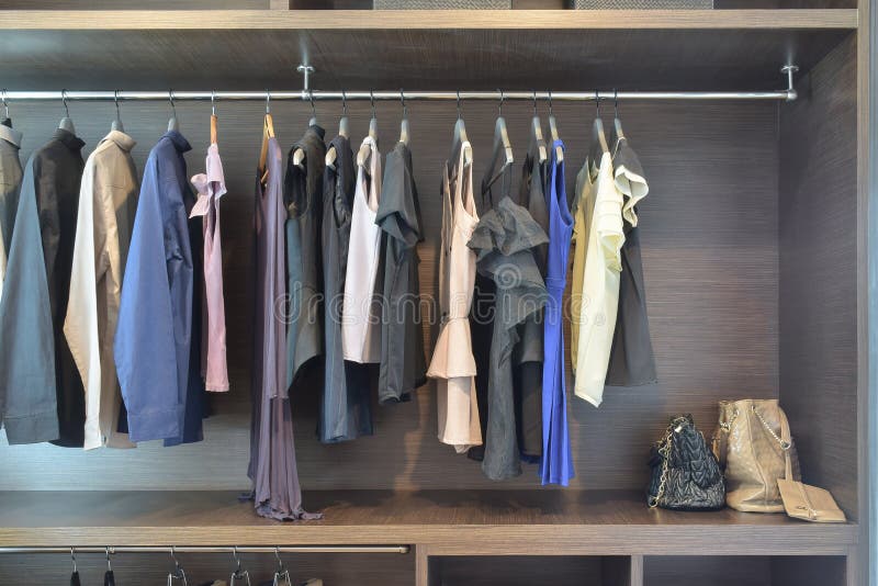 Stylish cloths in dark shade hanging in open wooden wardrobe royalty free stock photography Stylish cloths in dark shade hanging in open wooden wardrobe royalty free stock photography