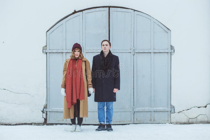 Stylish couple in classic suite standing near white historical building. Fashionable winter clothing stock image Stylish couple in classic suite standing near white historical building. Fashionable winter clothing stock image