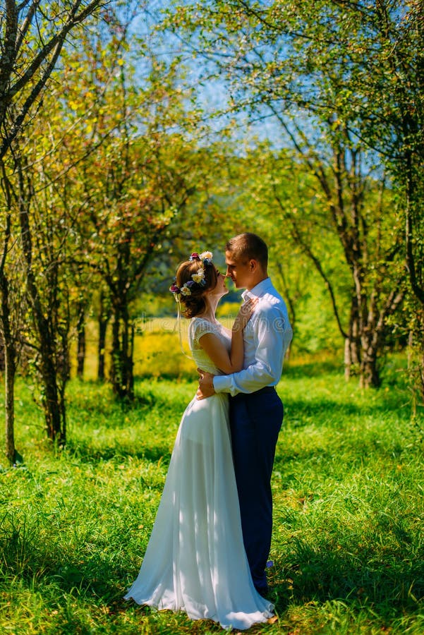 Stylish couple in love portrait, Newlywed husband and wife in circlet of flowers hugging near tree outdoors, summer nature concept stock images Stylish couple in love portrait, Newlywed husband and wife in circlet of flowers hugging near tree outdoors, summer nature concept stock images