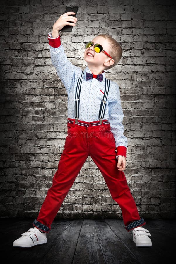 Stylish fashion boy making selfie on mobile phone, portrait.Kid`s fashion. stock photos Stylish fashion boy making selfie on mobile phone, portrait.Kid`s fashion. stock photos