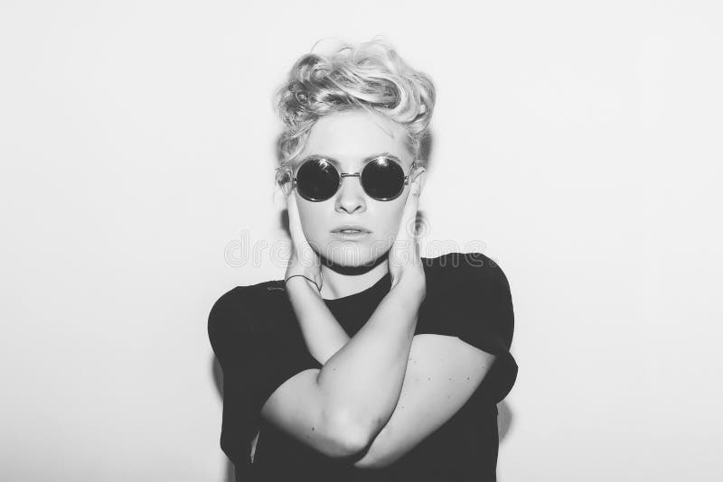 Stylish fashion blonde bad girl in a black t-shirt and rock sunglasses. Dangerous rocky emotional woman. white