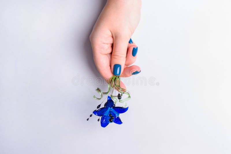 Stylish female manicure. Beautiful women`s hands on a gray background are holding a flower in their hands. Color concept