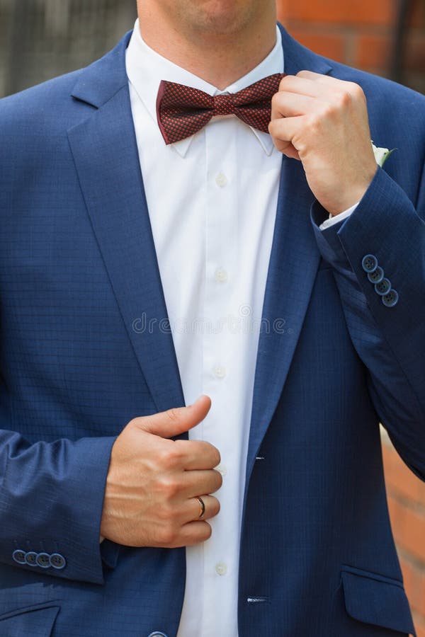 Stylish groom straightens a tie .