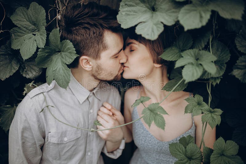 Stylish hipster couple kissing in green leaves, holding hands. m royalty free stock photo Stylish hipster couple kissing in green leaves, holding hands. m royalty free stock photo
