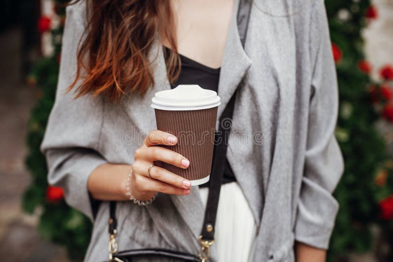 Stylish hipster girl with beautiful hair holding coffee cup in c