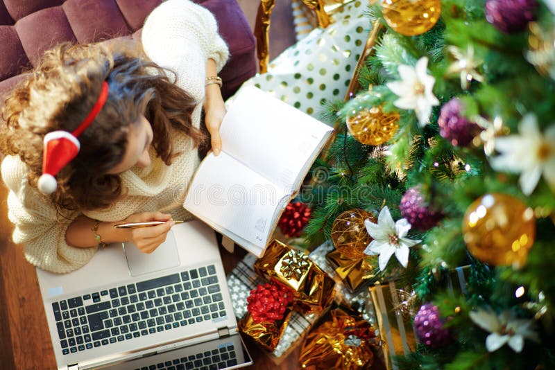 Stylish housewife with laptop and notepad making list stock image