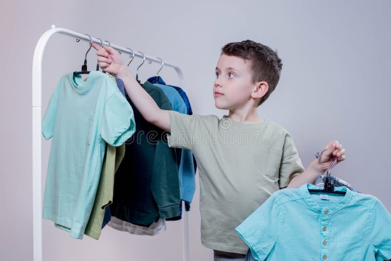 A Stylish Little Preschool Boy is Standing by the Clothes Rack, Looking ...