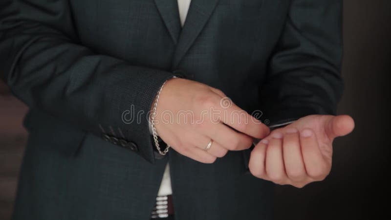 Stylish male businessman straightens his jacket.