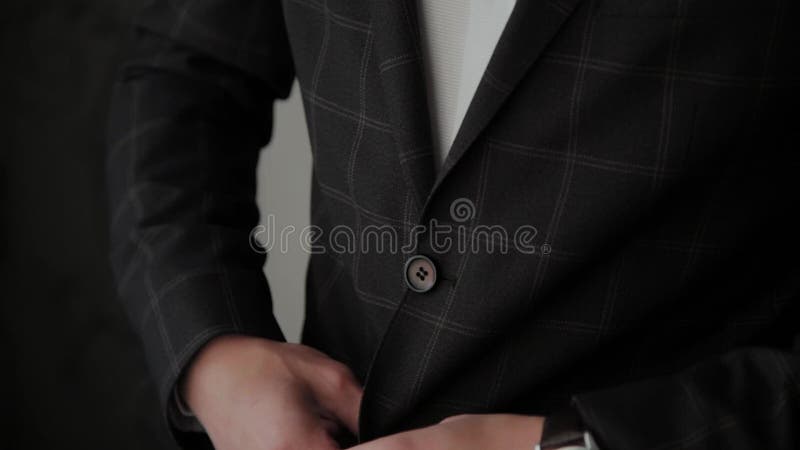 Stylish male businessman straightens his jacket.