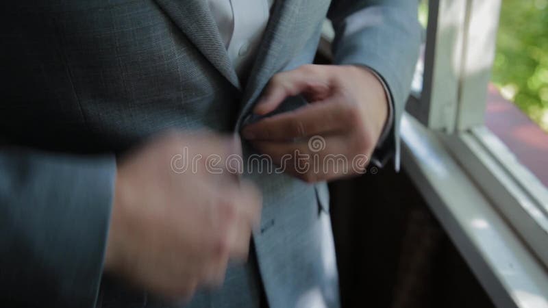 Stylish male businessman straightens his jacket.