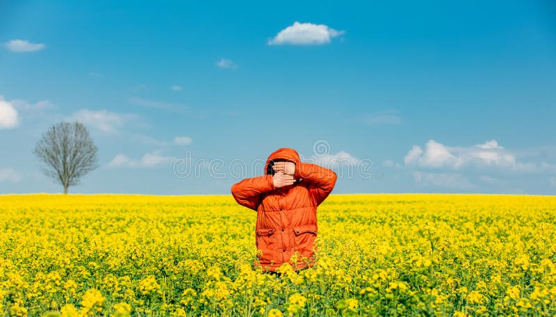 Stylish man in orange jacket in rapeseed field stock photos