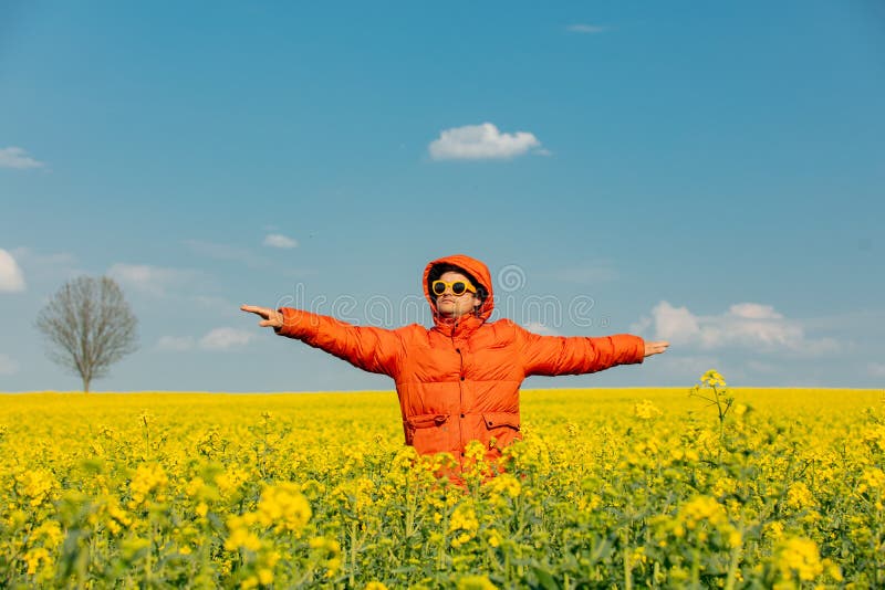 Stylish man in orange jacket in rapeseed field royalty free stock images