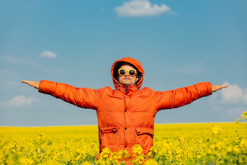 Stylish man in orange jacket in rapeseed field royalty free stock image