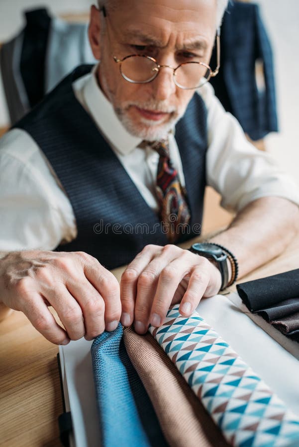 Stylish mature tailor looking at cloth samples royalty free stock image